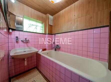 Koupelna s růžovými dlaždicemi, vanou a umyvadlem; dřevěné obložení dodává retro styl, původní zachovalý stav. | Prodej - dům/vila, 152 m²