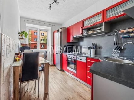 Moderní kuchyň s parketovou podlahou, červenou skříňkou a velkým oknem. Nabízí moderní spotřebiče a světlý interiér. | Pronájem bytu, 2+1, 60 m²