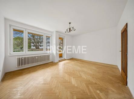 Světlý obývací pokoj s velkými okny, parketovou podlahou a moderním osvětlením, nabízí výhled do zahrady a vstup na balkon. | Prodej bytu, 3+1, 73 m²