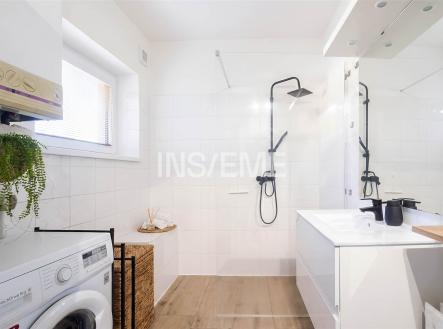 Moderní koupelna s dlažbou, sprchovým koutem a vestavěným umyvadlem; světlý prostor s moderními prvky a pračkou. | Prodej - dům/vila, 250 m²