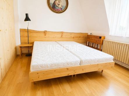 Prostorná ložnice s dřevěnou postelí, parketovou podlahou a vestavěnými skříněmi, světlý interiér díky velkým oknům a světlým stěnám. | Pronájem - dům/vila, 97 m²