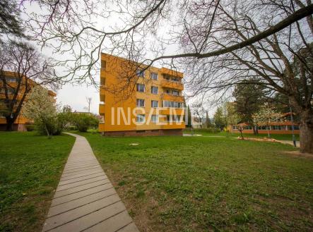 Čtyřpatrový panelový dům se žlutou fasádou, obklopený zeleným trávníkem a stromy, v klidné rezidenční čtvrti. | Prodej - malý objekt/garáž