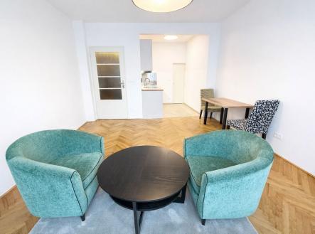 Světlý obývací pokoj s parketovou podlahou, moderním nábytkem a přístupem do otevřené kuchyně. Minimalistický design a velká okna | Pronájem bytu, 1+kk, 30 m²