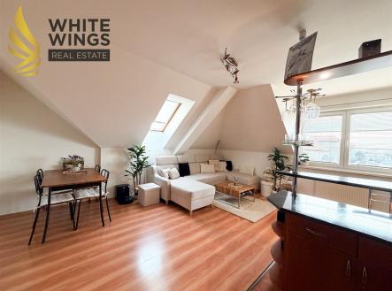 Podkrovní obývací pokoj s parketovou podlahou a velkými střešními okny, moderní nábytek a stylové osvětlení vytváří útulnou atmosféru. | Prodej bytu, 3+kk, 87 m²