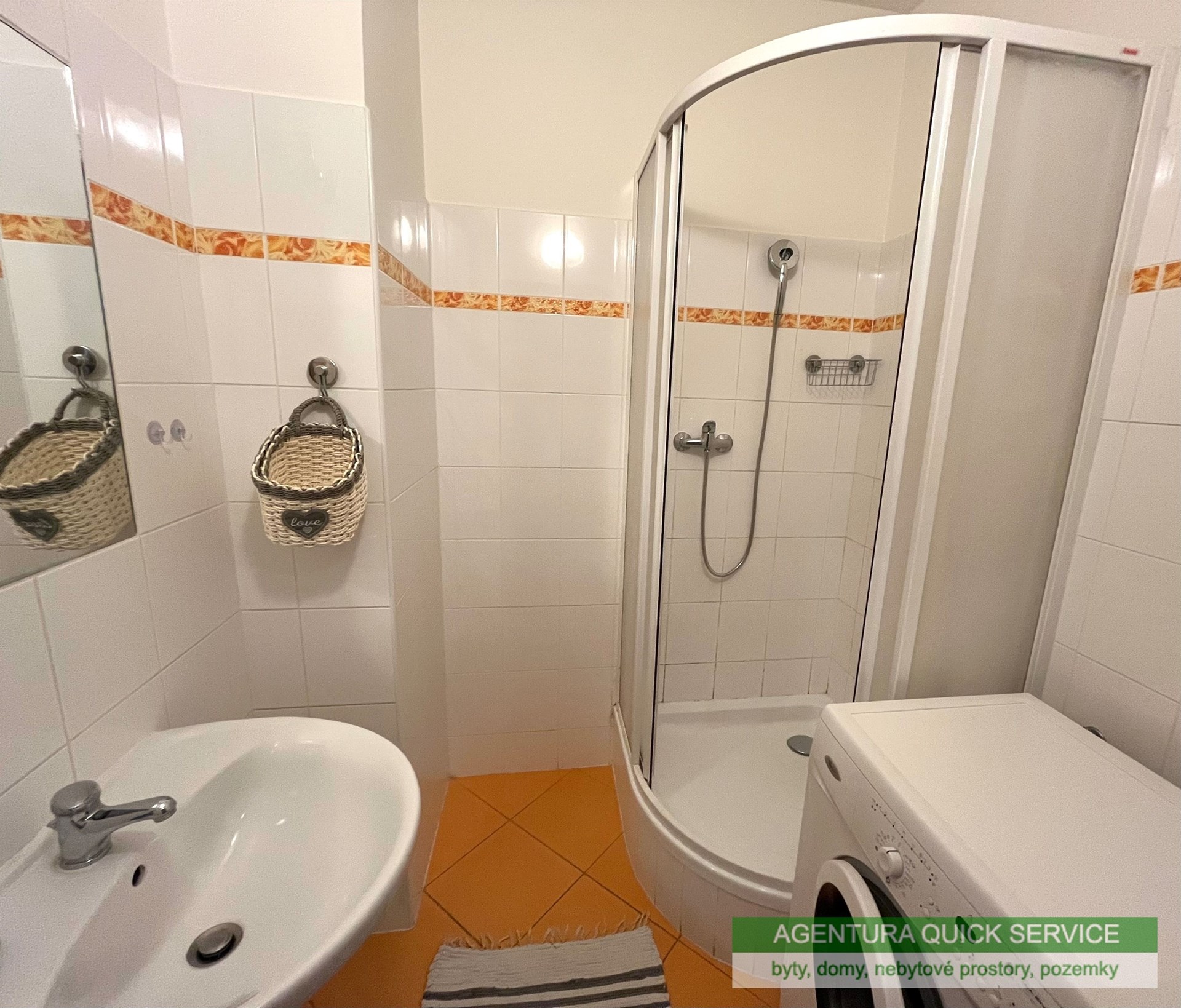 Kompaktní koupelna s moderním sprchovým koutem, dlažba v teplém odstínu, moderní obklady a umyvadlo, ideální pro rekonstrukci.