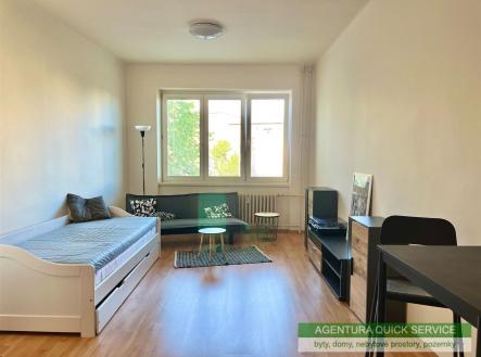 Světlý obývací pokoj s parketovou podlahou, velkými okny a moderním nábytkem, nabízí útulný prostor pro relaxaci. | Pronájem bytu, 1+kk, 33 m²