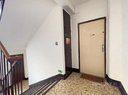 Chodba v bytovém domě s dlažbou, dveře do bytu, schodiště se zábradlím, světlé stěny, dobře udržovaný prostor. | Pronájem bytu, 2+1, 70 m²
