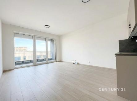 Světlý obývací pokoj s moderní parketovou podlahou, velká okna vedoucí na balkon, novostavba v minimalistickém stylu. | Pronájem bytu, garsoniéra, 36 m²