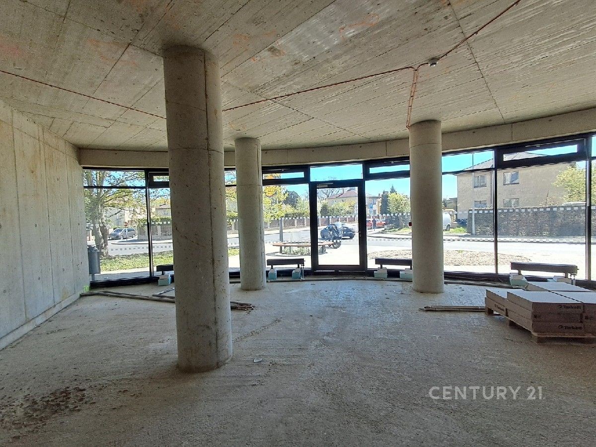 Otevřený moderní prostor s betonovou stěnou, velkými okny a rozestavěnou podlahou, ideální pro individuální dokončení.