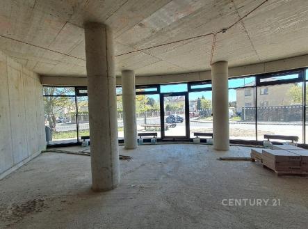 Otevřený moderní prostor s betonovou stěnou, velkými okny a rozestavěnou podlahou, ideální pro individuální dokončení. | Prodej - obchodní prostor, 84 m²