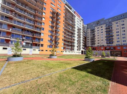 Moderní bytový komplex s balkony, parková úprava s udržovaným trávníkem a betonovými prvky, ideální pro klidné bydlení v městské části. | Pronájem bytu, 2+kk, 43 m²