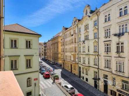 Pohled z balkonu na historické budovy s dekorativními fasádami, klidná dlážděná ulice, ideální městská lokalita pro bydlení. | Pronájem bytu, 2+1, 87 m²