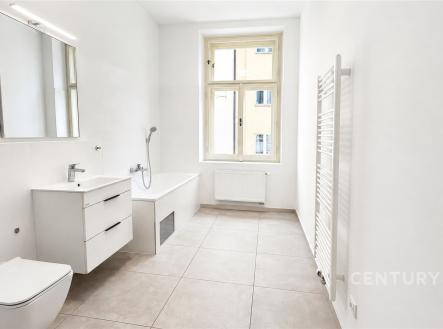 Světlá koupelna s moderní keramickou dlažbou, velkým oknem a nástěnným topením, čistý a minimalistický design. | Pronájem bytu, 2+1, 87 m²