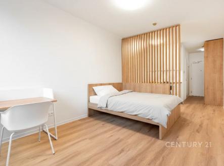 Prostorná ložnice s parketovou podlahou, dřevěnou příčkou a moderním nábytkem, ideální pro komfortní bydlení. | Prodej bytu, 1+kk, 32 m²
