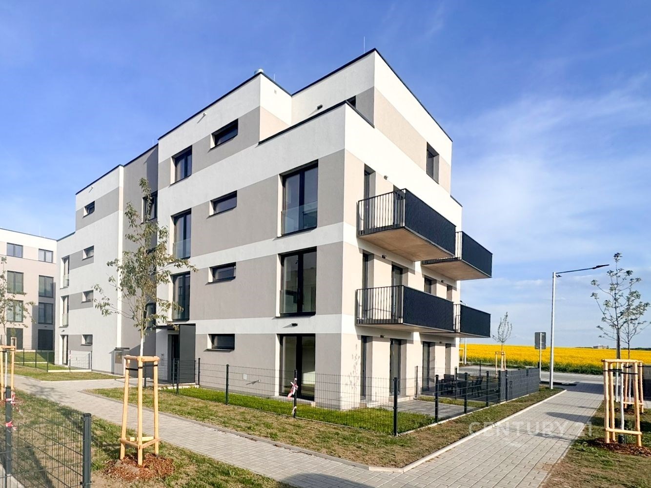 Moderní bytový dům s balkony, minimalistická architektura, kvalitní fasádní úpravy, klidná lokalita s upraveným okolím v blízkosti přírody.