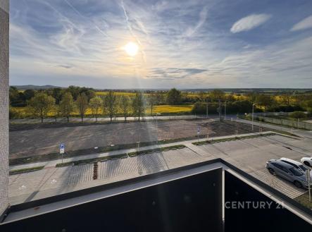 Výhled z balkonu s moderním zábradlím nabízí panoramatický pohled na krajinu a parkoviště, ideální pro milovníky přírody a klidného bydlení. | Pronájem bytu, 2+kk, 44 m²