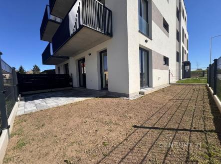 Předzahrádka s dlažbou a trávníkem, moderní novostavba, balkon a velká okna, klidné prostředí. | Prodej bytu, 1+kk, 39 m²