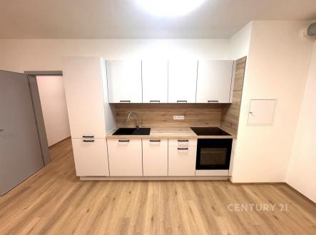 Moderní kuchyň s parketovou podlahou, světlými bílými skříňkami a dřevěným obkladem, vestavěné spotřebiče, minimalistický design. | Pronájem bytu, 1+kk, 39 m²