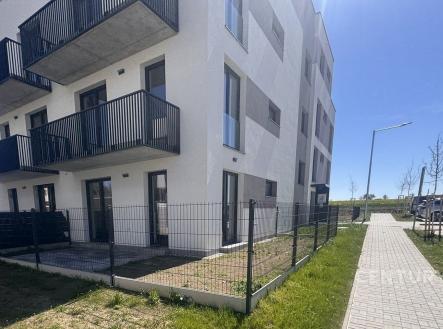 Moderní bytový dům s balkony, bílou fasádou a udržovaným trávníkem, v klidné lokalitě. | Pronájem bytu, 1+kk, 39 m²