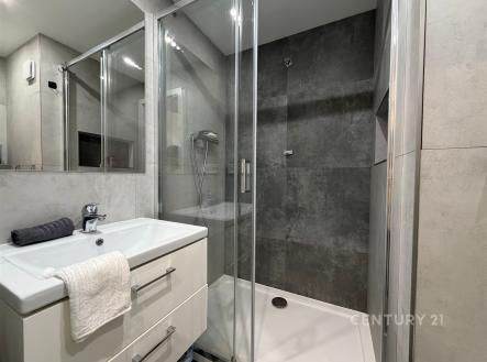 Moderní koupelna s proskleným sprchovým koutem, dlažbou a vestavěným umyvadlem. Světlý interiér s elegantním designem. | Pronájem bytu, 2+kk, 60 m²