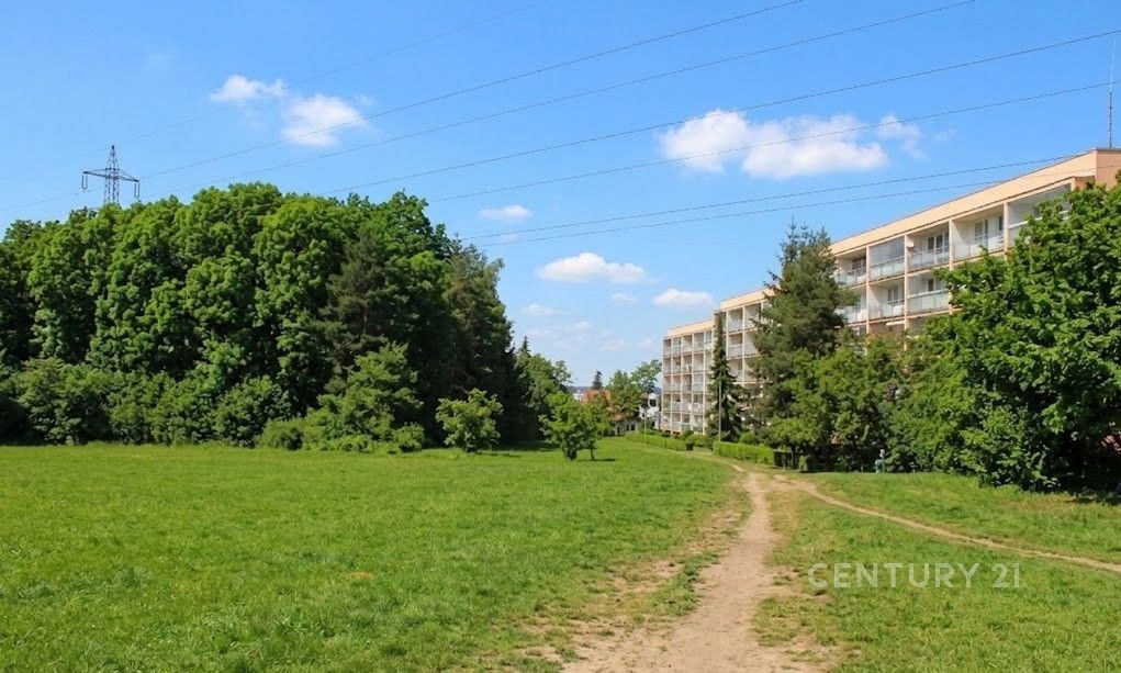Travnatá plocha s rekreační cestou sousedí s bytovým domem. Klidná lokalita obklopená zelení, ideální pro rodiny hledající přírodu blízko města.