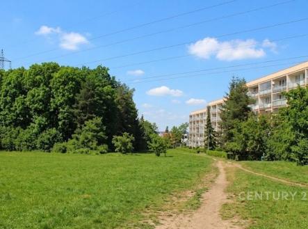 Travnatá plocha s rekreační cestou sousedí s bytovým domem. Klidná lokalita obklopená zelení, ideální pro rodiny hledající přírodu blízko města. | Prodej - pozemek pro bydlení, 1 145 m²