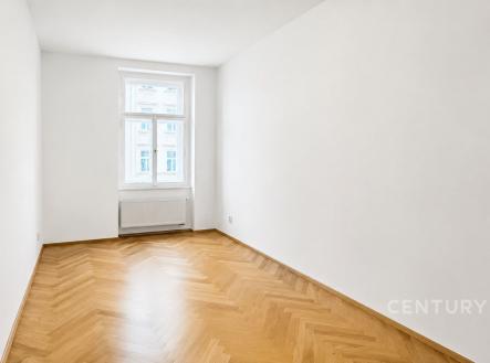 Světlý pokoj s parketovou podlahou, bílými stěnami a velkým oknem, ideální pro moderní interiérové úpravy. | Pronájem bytu, 2+kk, 50 m²