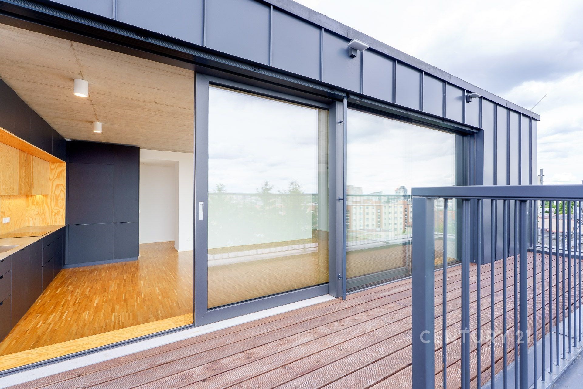 Velký balkon s dřevěnou podlahou sousedí s moderním obývacím pokojem. Velká okna zajišťují dostatek světla, parketová podlaha v interiéru.