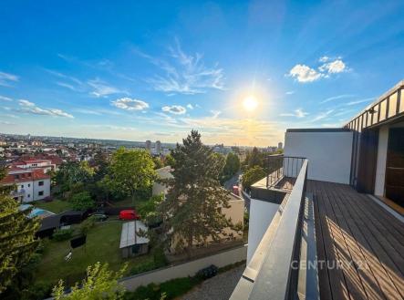 Pohled z balkonu s dřevěnou podlahou, výhled na město a zeleň, západ slunce, moderní styl, klidná lokalita, atraktivní prostředí. | Prodej bytu, 4+kk, 121 m²