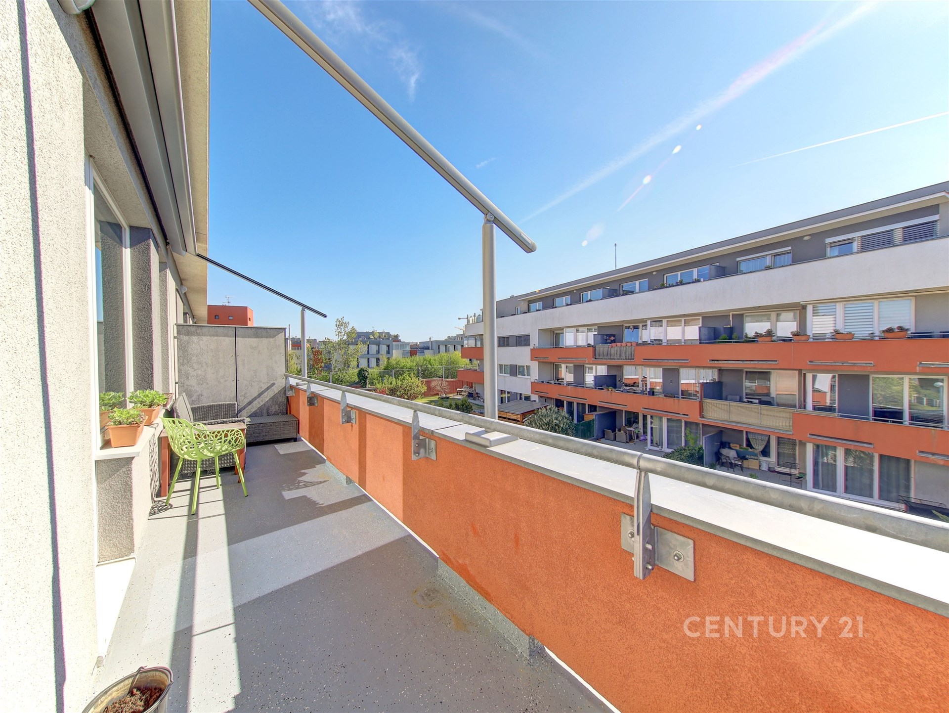 Prostorný balkon s betonovou podlahou a moderním zábradlím nabízí otevřený výhled, ideální pro relaxaci na slunných dnech.