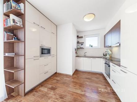 Moderní kuchyň s parketovou podlahou, světlými vestavěnými skříněmi a velkými okny. | Prodej bytu, 2+kk, 60 m²